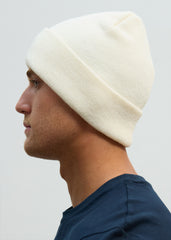A person wearing an OCL off-white knit beanie hat.