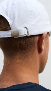 A person viewed from the back wearing a white baseball cap with black embroidery, featuring an adjustable clasp with an OCL logo.
