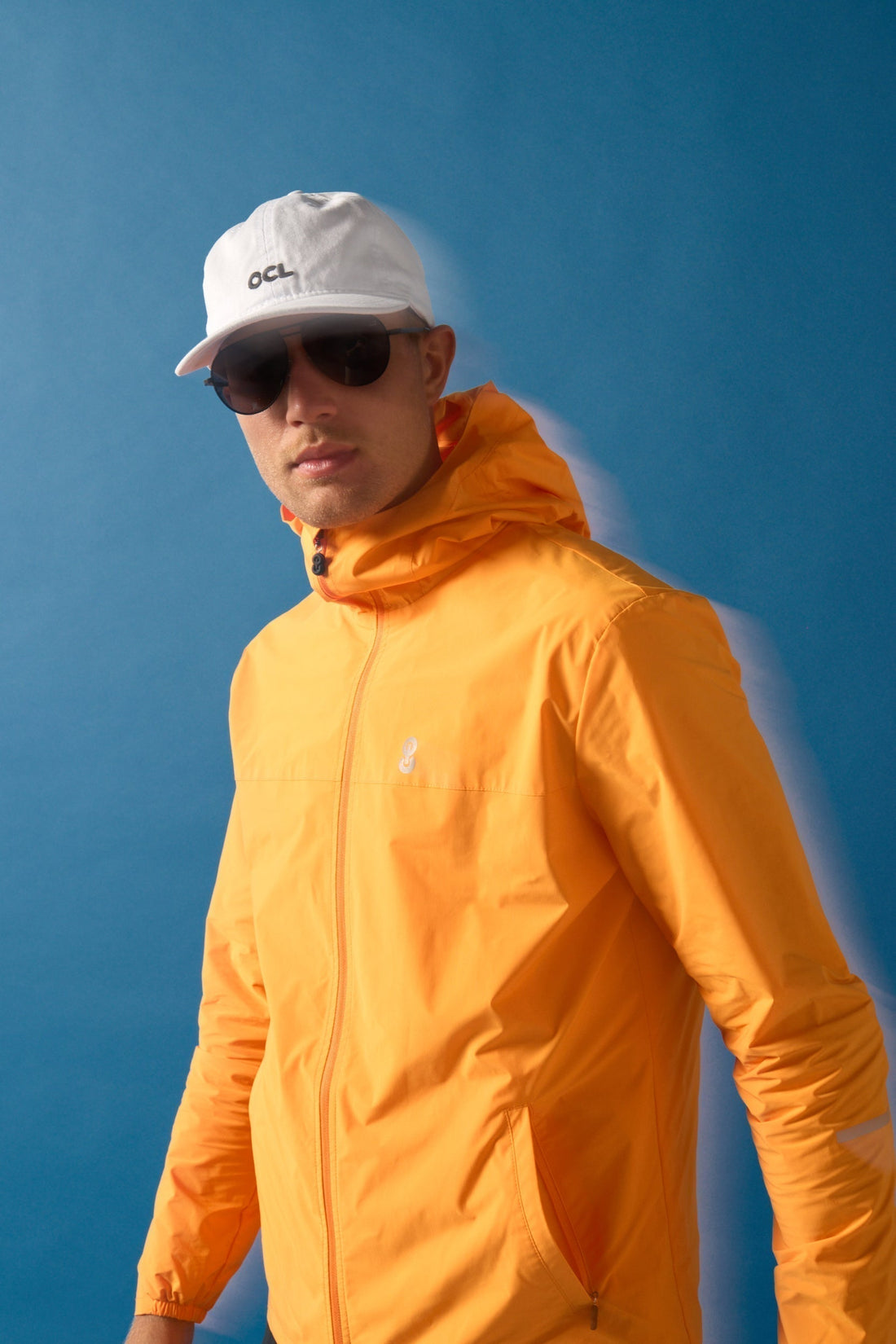 Orange OCL windbreaker and white OCL cap worn for a city workout