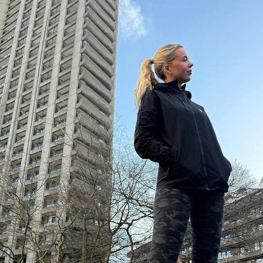 Person in a black OCL jacket standing in front of a tall building